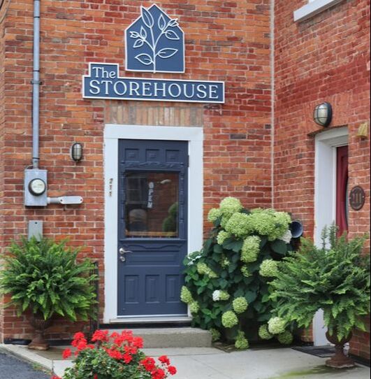 a storefront image of the Storehouse in Port Stanley. The door is blue and the building is strawberry brick. 
