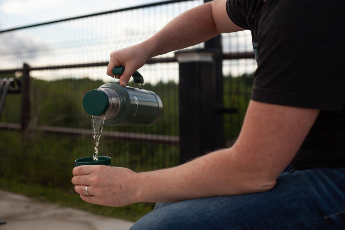 A person pours tea from a Stanley Thermos while sitting at the St. Thomas Elevated park