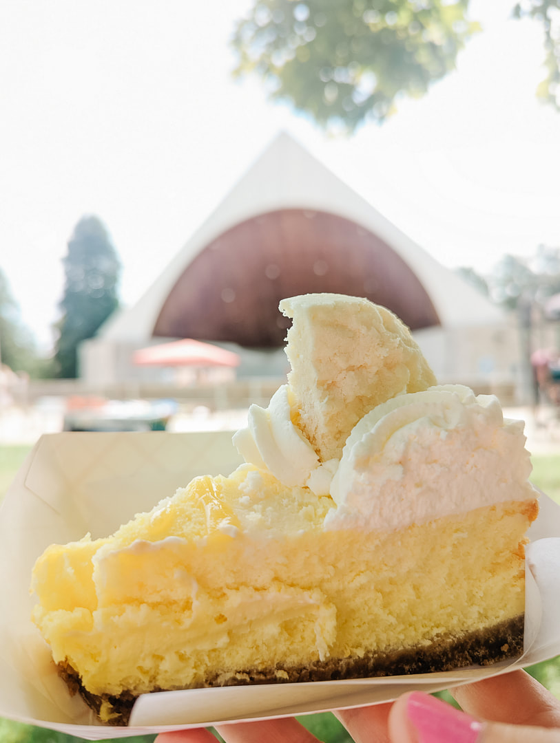 A slice of cheese cake from Ruby Blues bakery, the bandshell at Pinafore Park is in the background
